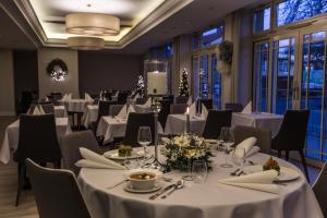 jadalnia z białymi stołami i krzesłami oraz oknami w obiekcie Villa Bravo & SPA w mieście Międzyzdroje