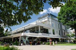 een groot wit gebouw met mensen die ervoor lopen bij Hotel ABC in Leskovac