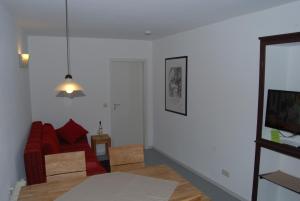een woonkamer met een rode bank en een tv bij Kronenhof - Wein und Ferien in Gau-Algesheim
