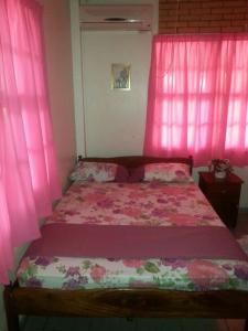 Dormitorio rosa con cama con cortinas rosas en Villa Nickerie/ Suriname, en Nieuw Nickerie