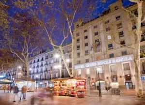 a group of people walking down a city street at night at Hotel SERHS Rivoli Rambla in Barcelona