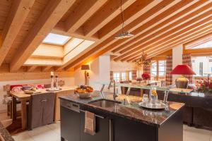 a kitchen with a large island in a room with wooden ceilings at Vrony Apartments by Hotel Walliserhof Zermatt in Zermatt