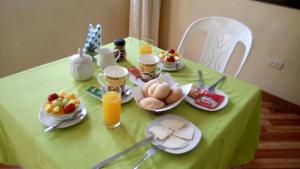 zielony stół ze śniadaniem i napojami w obiekcie Hostal Geminis w mieście Ica