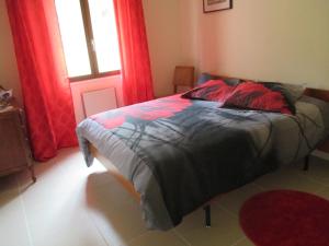 Saint-Amand-en-PuisayeにあるLa Griotterieのベッドルーム1室(赤いカーテンと窓付きのベッド1台付)