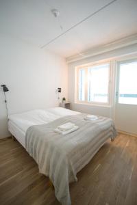 um quarto branco com uma cama grande e 2 janelas em Aurora City Center Suite em Rovaniemi