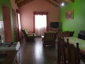 uma sala de estar com paredes verdes e uma mesa e cadeiras em Cabañas Años Verdes em Sarmiento