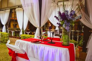 una mesa roja y blanca con un jarrón de flores. en Hotel Temático Mision Colonial en San Cristóbal de Las Casas