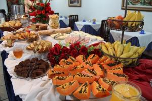 une table remplie de denrées alimentaires, de fruits et de légumes dans l'établissement Js Palace Hotel, à Alfenas