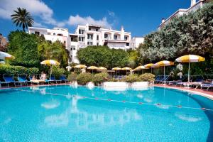 una grande piscina con ombrelloni e persone sedute intorno ad essa di Hotel Ulisse a Ischia