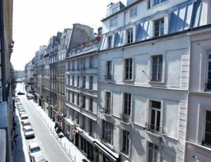 a city street with cars parked in front of buildings at Hôtel du Pont Neuf in Paris