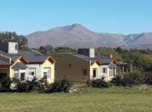 un groupe de maisons dans un champ avec des montagnes en arrière-plan dans l'établissement Cabañas De Los Tios, à Sierra de la Ventana