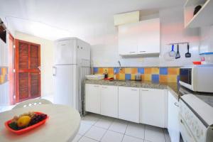 a white kitchen with a bowl of fruit on a table at Merepe Residencial in Porto De Galinhas