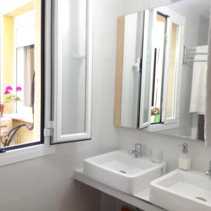 a bathroom with two sinks and two mirrors at Hostal Casa Chueca in Madrid