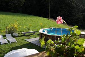 a hot tub in a yard with chairs and an umbrella at Appartement Orion à Saint Gervais, proche Chamonix in Saint-Gervais-les-Bains