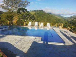 a pool with chairs and mountains in the background at Pousada Antigo Caminho Do Ouro in Cunha