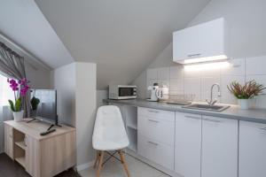 a white kitchen with a white chair and a sink at Willa Przystań in Jastarnia
