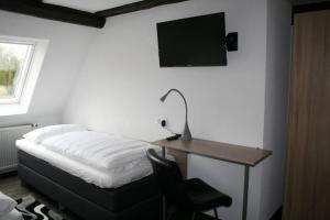a bedroom with a desk with a bed and a television at Landhotel Schwarzer Adler in Tiefenbronn