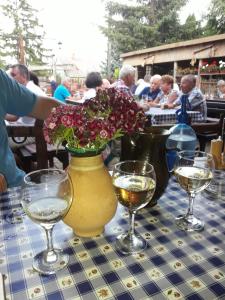 a vase with flowers on a table with wine glasses at Sweet Apartman Zalakaros in Zalakaros