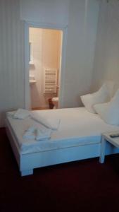 a white bed with two pillows on top of it at Casa Ghetu Fundeni in Bucharest