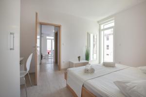 a white bedroom with a large bed and a table at Villa Podgorka in Podgora