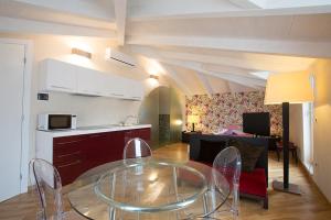 a living room with a glass table and a kitchen at Bed&Breakfast JSuite in Gioia del Colle