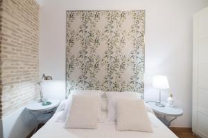 セビリアにあるLas Columnas de Juliaの白いベッドと壁紙が備わるベッドルーム1室が備わります。
