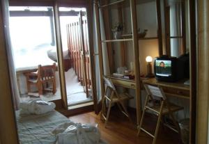 Habitación con escritorio, TV y mesa con sillas. en Il Fraitevino hotel bed & breakfast en Sestriere
