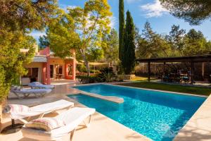 einen Pool mit zwei Liegestühlen und ein Haus in der Unterkunft Can Jaume Curt in Sant Rafael de Sa Creu