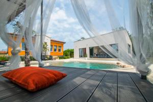 ein Bett auf einer Terrasse neben einem Pool in der Unterkunft Villa Franka Nedešćina in Nedeščina