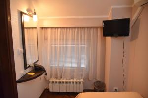 een slaapkamer met een raam met een televisie aan de muur bij B&B Park in Sremčica