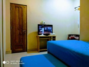 a bedroom with a blue bed and a television at Wijilan60 Syariah in Yogyakarta