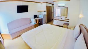 1 dormitorio con cama blanca y espejo en P.A. Place Hotel en Nakhon Sawan