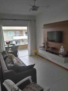 a living room with a couch and a flat screen tv at Verano Residencial in Guarajuba