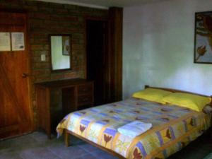 1 dormitorio con cama y pared de ladrillo en Hostal Las Palmas, en Puyo