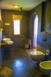 a bathroom with two sinks and a toilet and a window at Sigiri Arana Luxury Chalets in Sigiriya