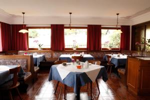 un restaurante con mesas, sillas y cortinas rojas en Garnì Iosc, en San Vigilio Di Marebbe