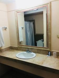 a bathroom with a sink and a large mirror at Hotel Suites Kino in Hermosillo