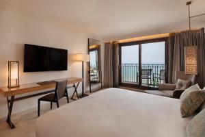 a hotel room with a bed and a desk with a television at The Setai Tel Aviv in Tel Aviv