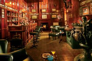 een kamer met een bar met groene stoelen en tafels bij WelcomHeritage Fernhills Royal Palace in Ooty