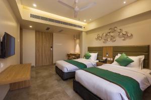 a hotel room with two beds and a flat screen tv at Floressa Randa, Porur in Chennai