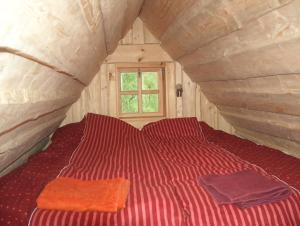 a bed in a wooden room with two towels on it at Zirgu sēta "Klajumi" - Horse ranch "Klajumi" in Kaplava