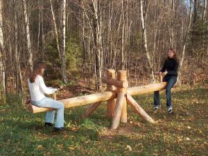 two women sitting on a wooden bench in the woods at Zirgu sēta "Klajumi" - Horse ranch "Klajumi" in Kaplava