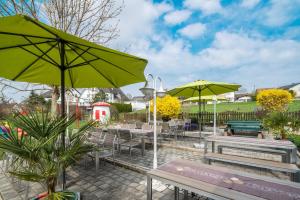 un patio con mesas, sillas y sombrillas en Hotel Goldener Löwe, en Günzburg