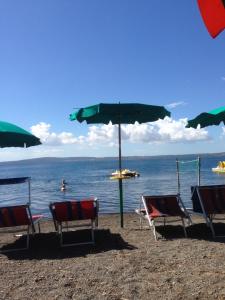- un groupe de chaises et un parasol sur une plage dans l'établissement Casa Belvedere, à Mazzano Romano