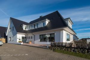 a white house with a black roof at Hotel Berlin in Wenningstedt