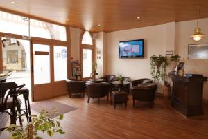 a waiting room with chairs and a table and a tv at Logis - Hôtel Le Caddy in Le Touquet-Paris-Plage