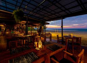 a dining room table with chairs and umbrellas at Bangsak Village - Adults Only - SHA Extra Plus in Khao Lak