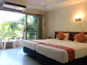 two beds in a hotel room with a balcony at Wild Orchid Villa Krabi in Ao Nam Mao