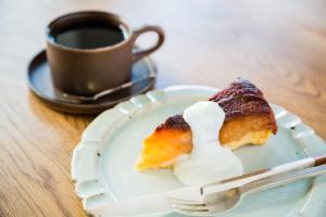 a plate with a piece of pastry and a cup of coffee at Guest House Kura in Suzaka