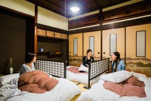 three women sitting on beds in a room at Guest House Kura in Suzaka